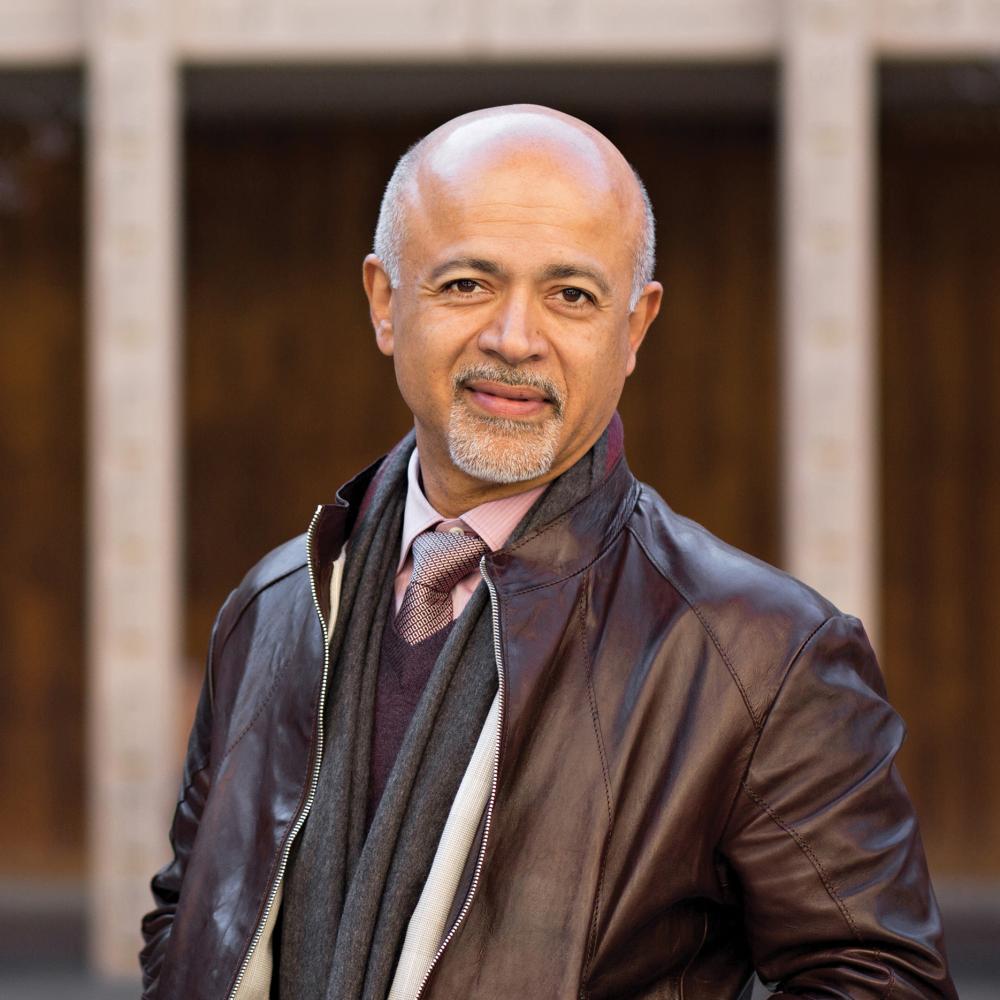 Abraham Verghese, in a leather jacket with his hands in his pockets