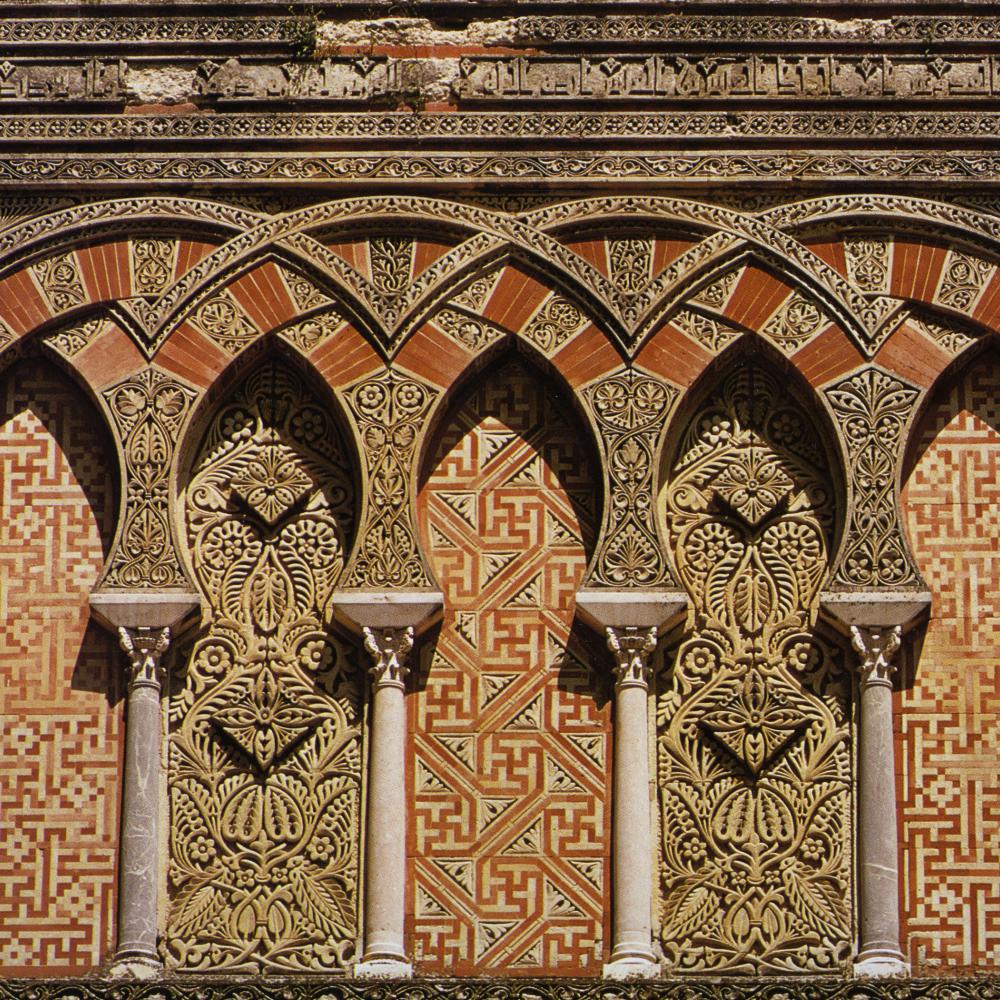 Inerlacing arches decorated with intricate floral and geometric patterns in red and gold