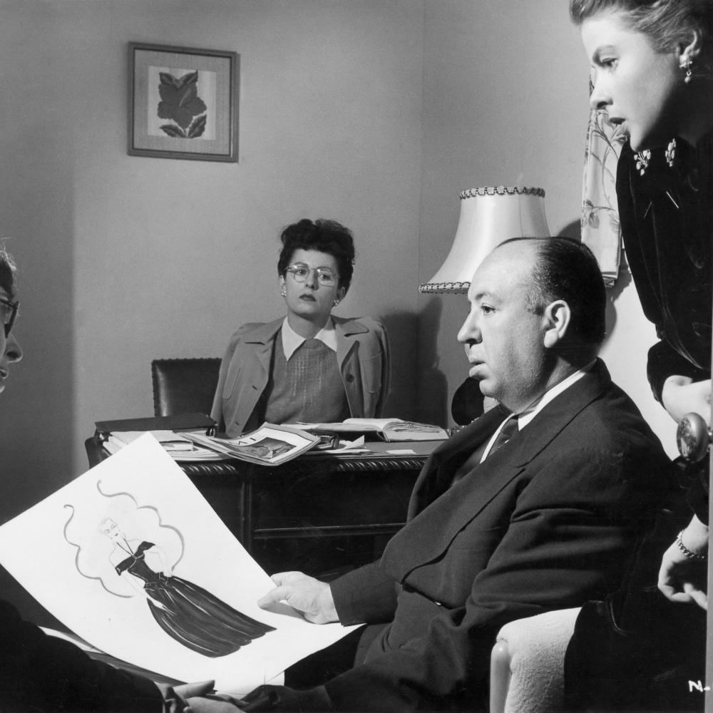 black and white photograph of man in chair in foreground, woman at desk in background