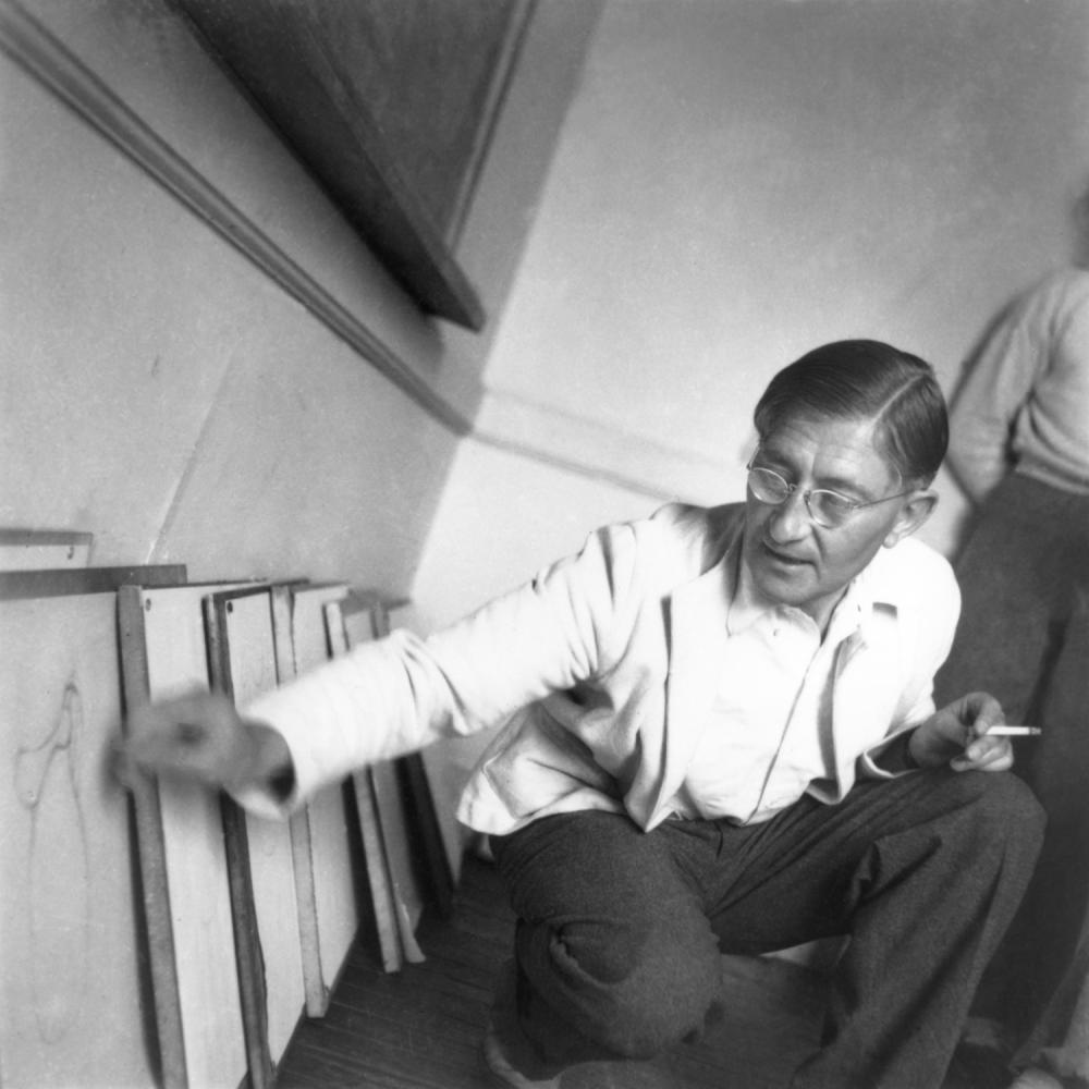 Albers holding a cigarette and kneeling in front of several diagrams