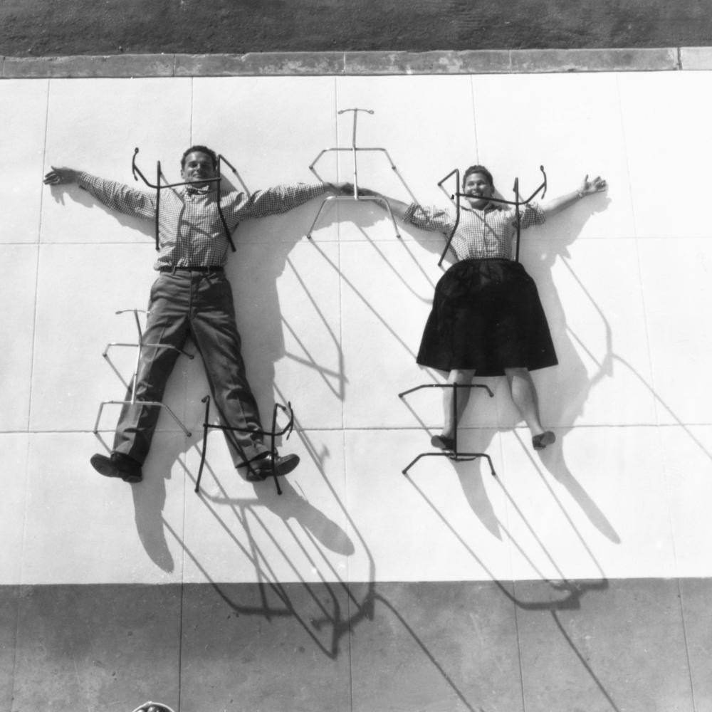 A man and a woman spread out in snow angel fashion over a concrete block, to which they are pinned by rods.