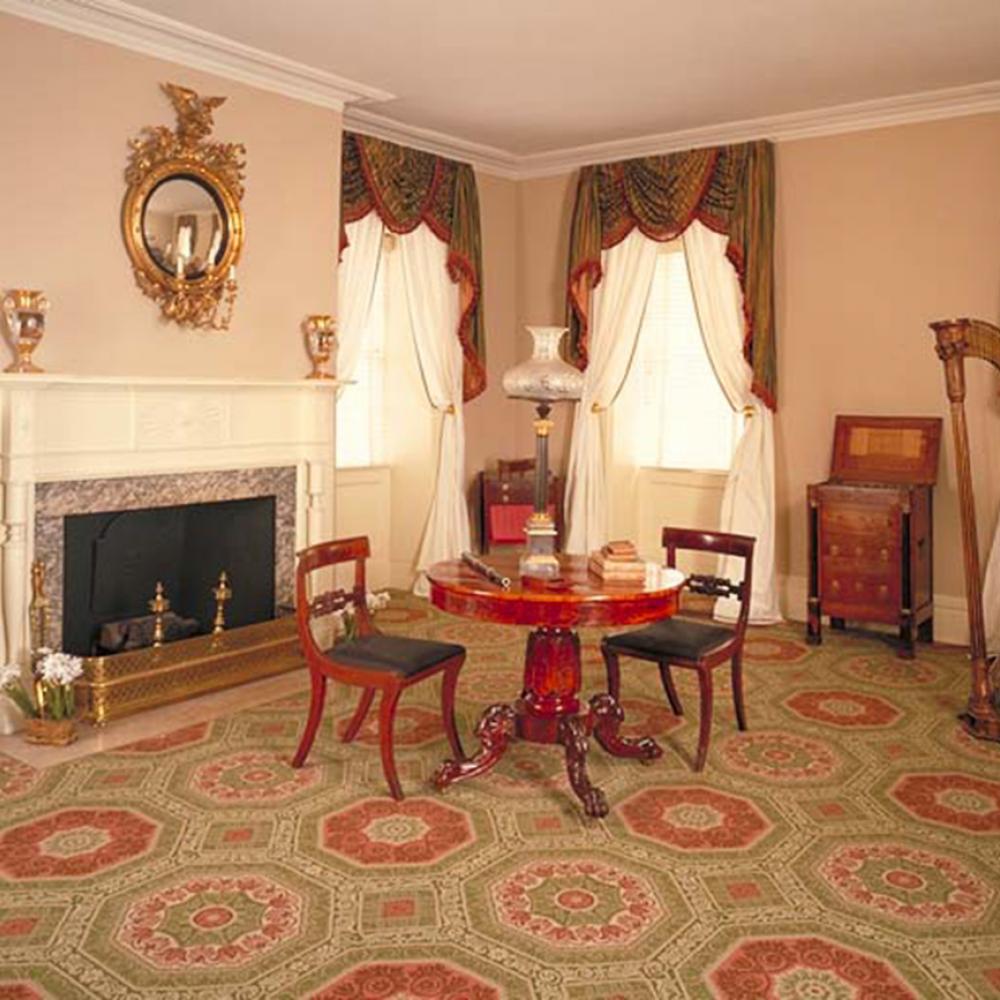 Color photo of an elegant parlor with a table and two chairs at its center.