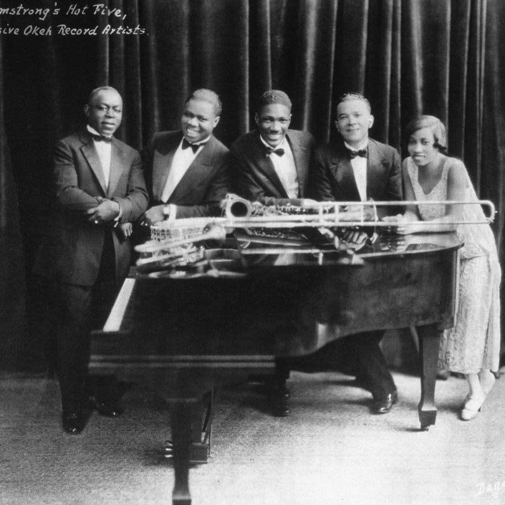 The hot five pose around a grand piano