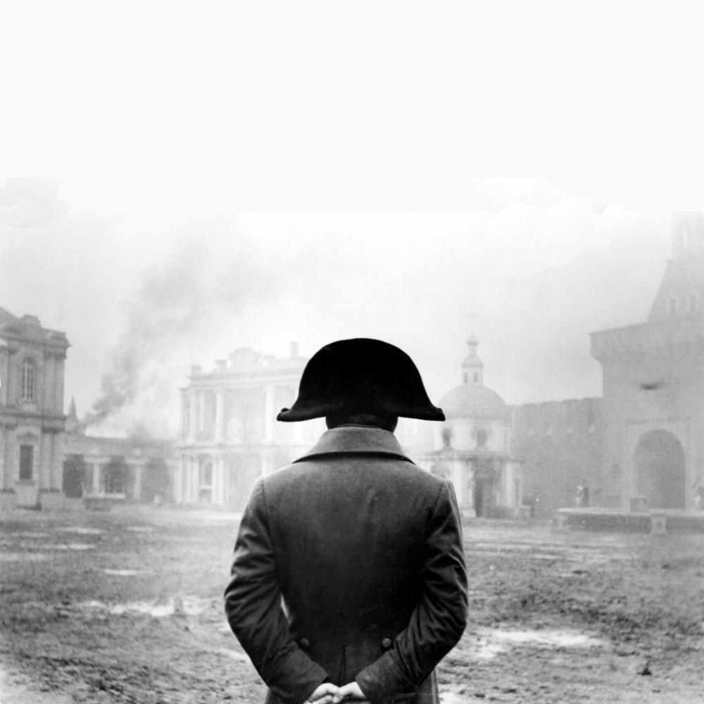 Black and white photo of Napoleon facing away from the camera, down-range, beholding a city plaza.