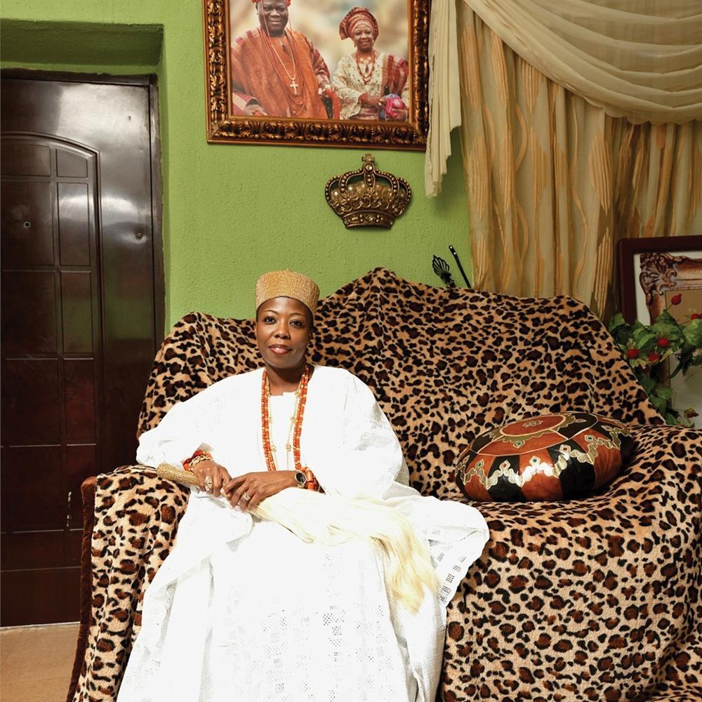 HRM Princess Dr. Adetutu Adebiyi Adesida, seated on a leopard print couch, wearing a write dress