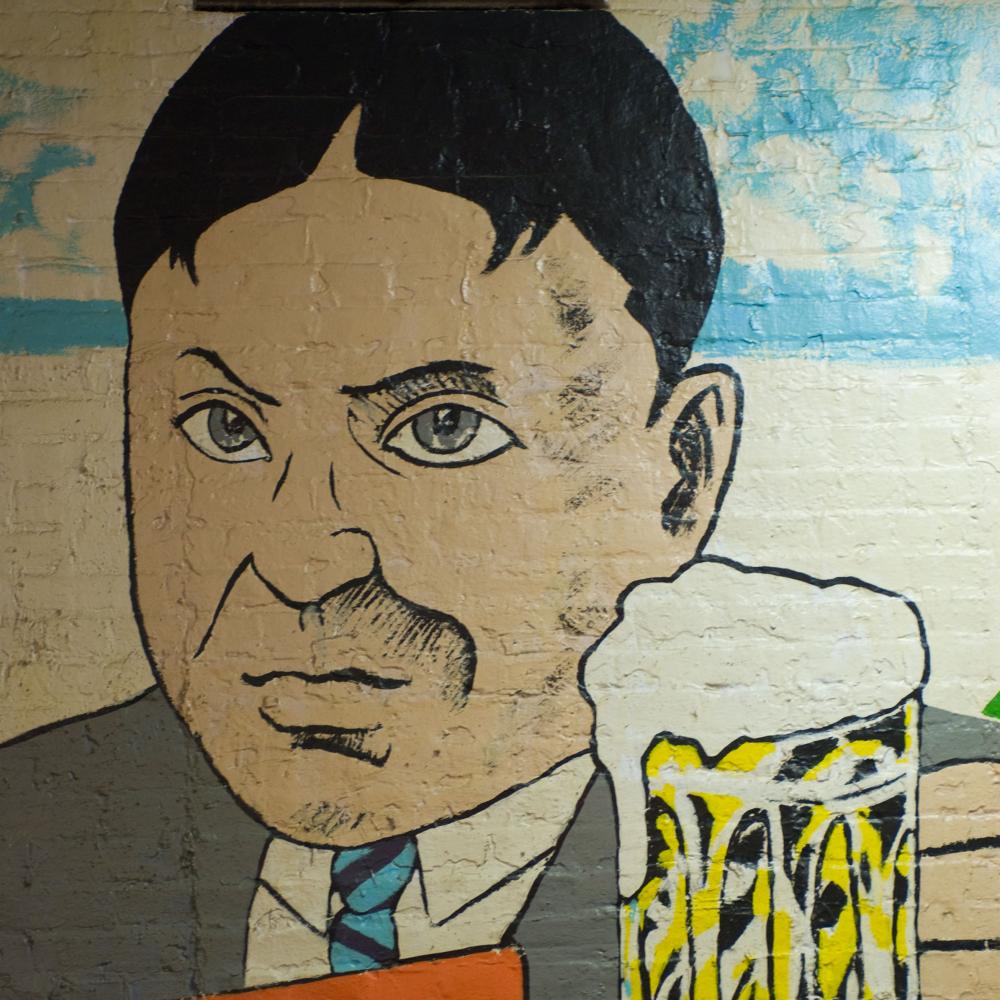 mural painting of a man in a suit holding up a beer