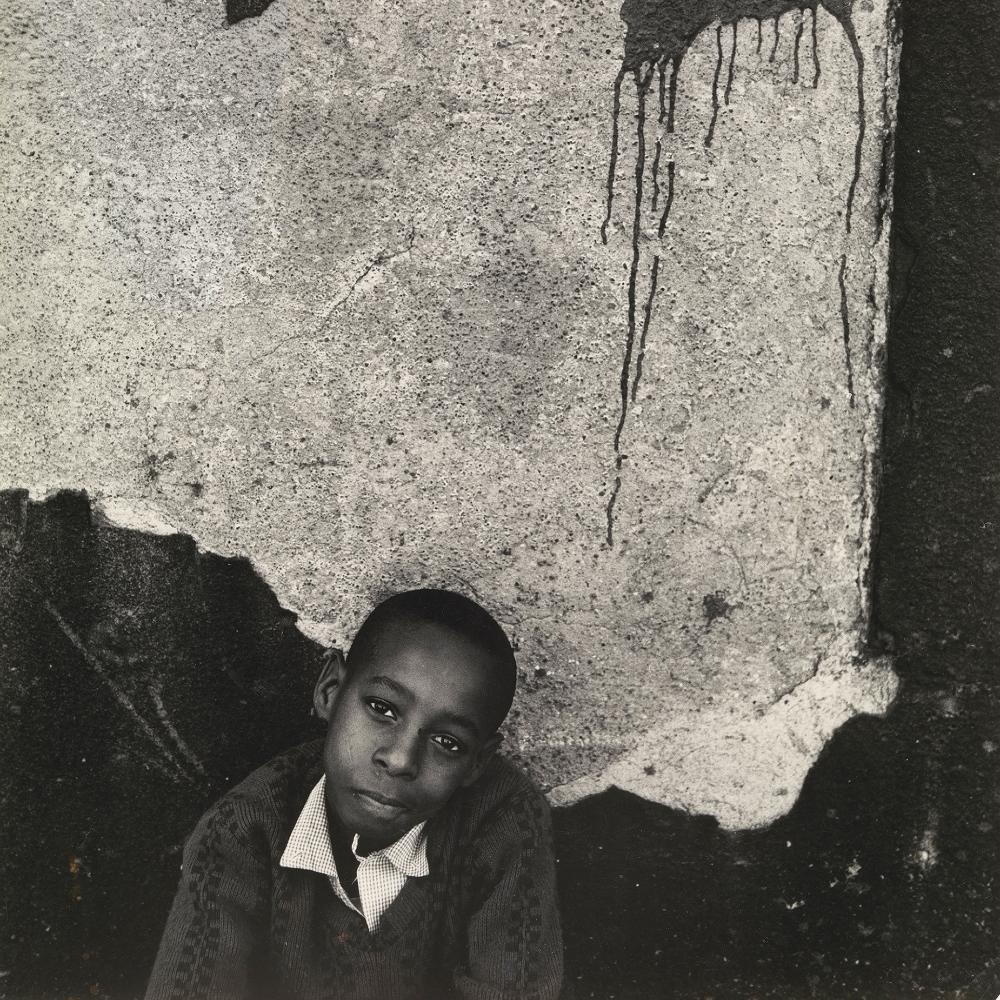 photo of a young a boy around nine years old posing before a cracked cement wall