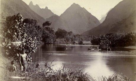 Early photograph of native fishermen in a river with mountains in the distance