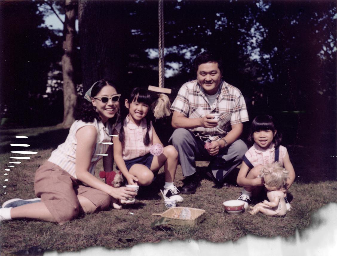 family sitting on the grass, smiling