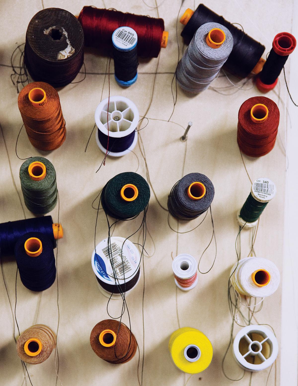 Multiple spools of multi-colored thread are arranged on a white wood table