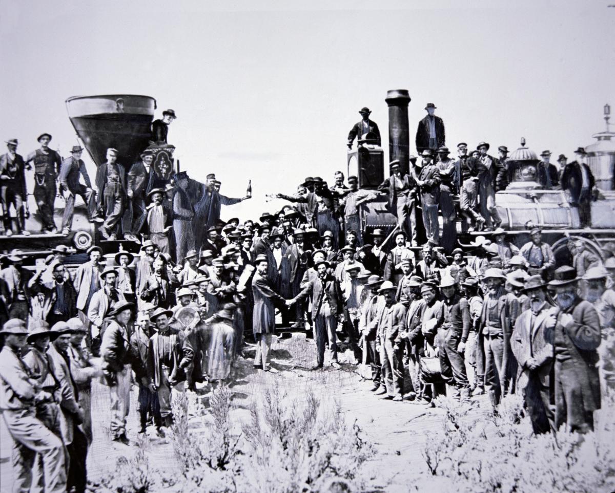 Black and white photograph of railroad workers standing on top of and in front of trains