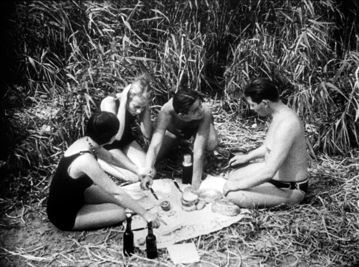 black and white photo of three women and a man sitting on the ground