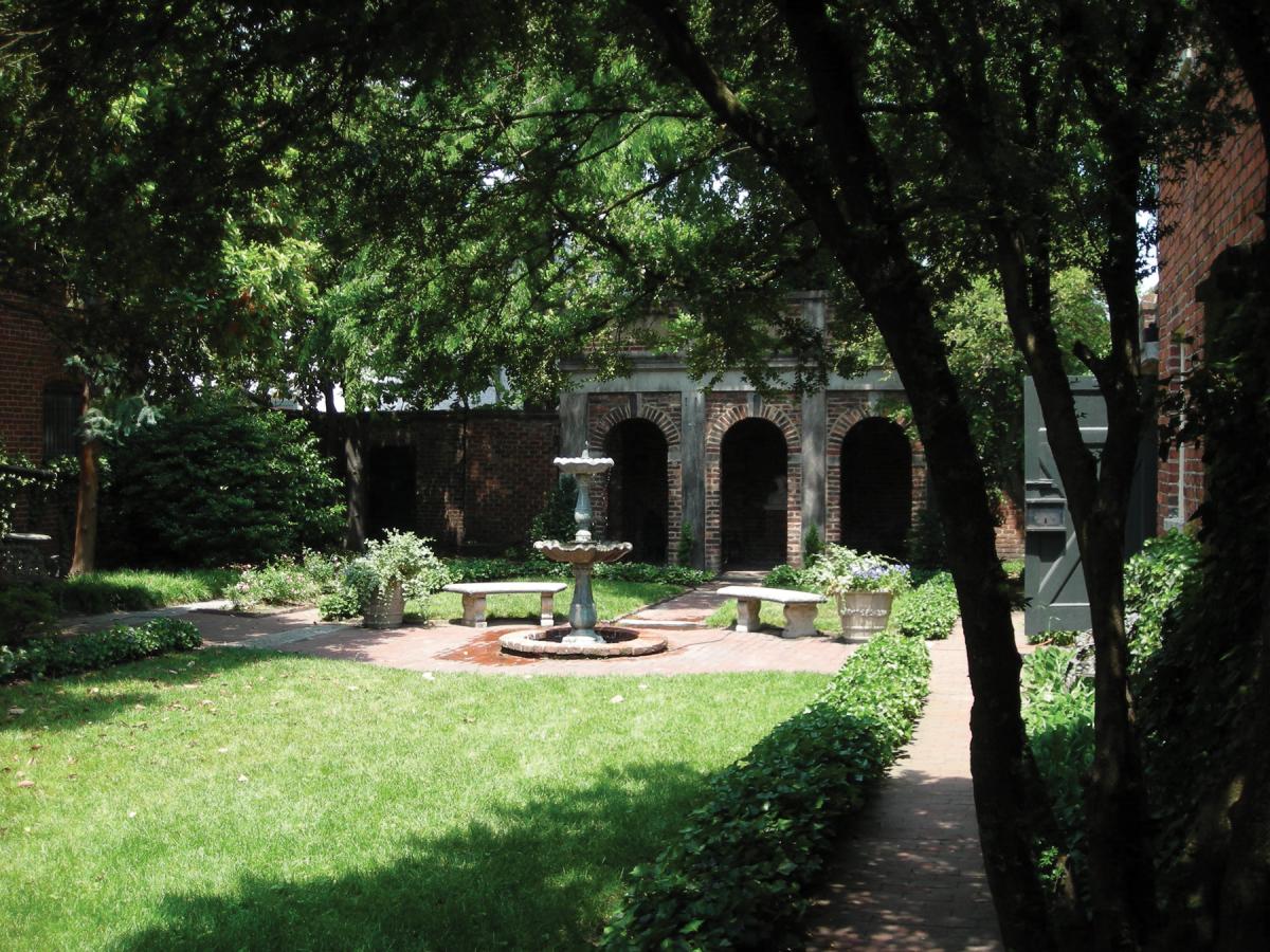 Photograph of a small courtyard with brick arches in background