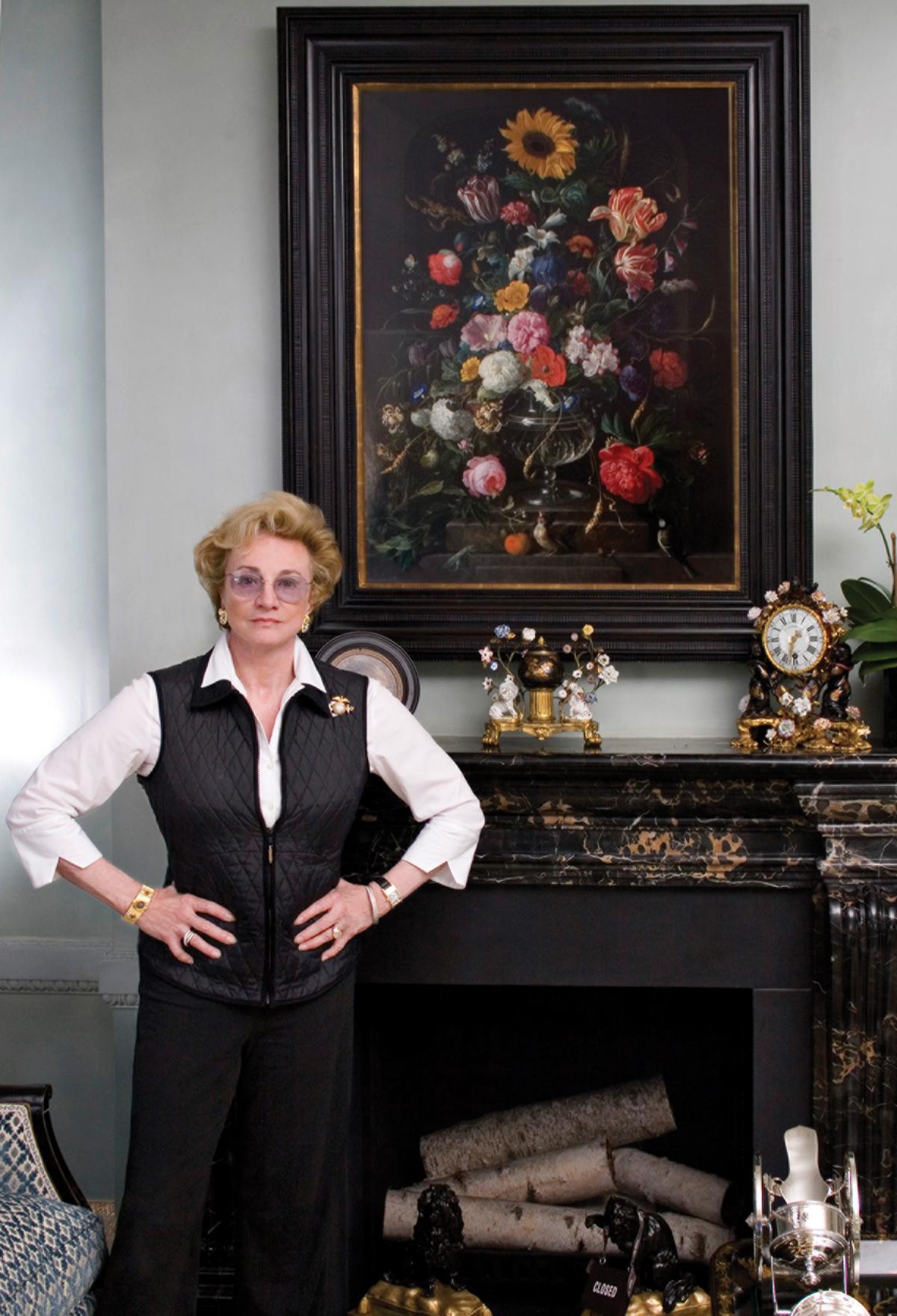 Photograph of a woman standing in front of a painting that hangs above a fireplace