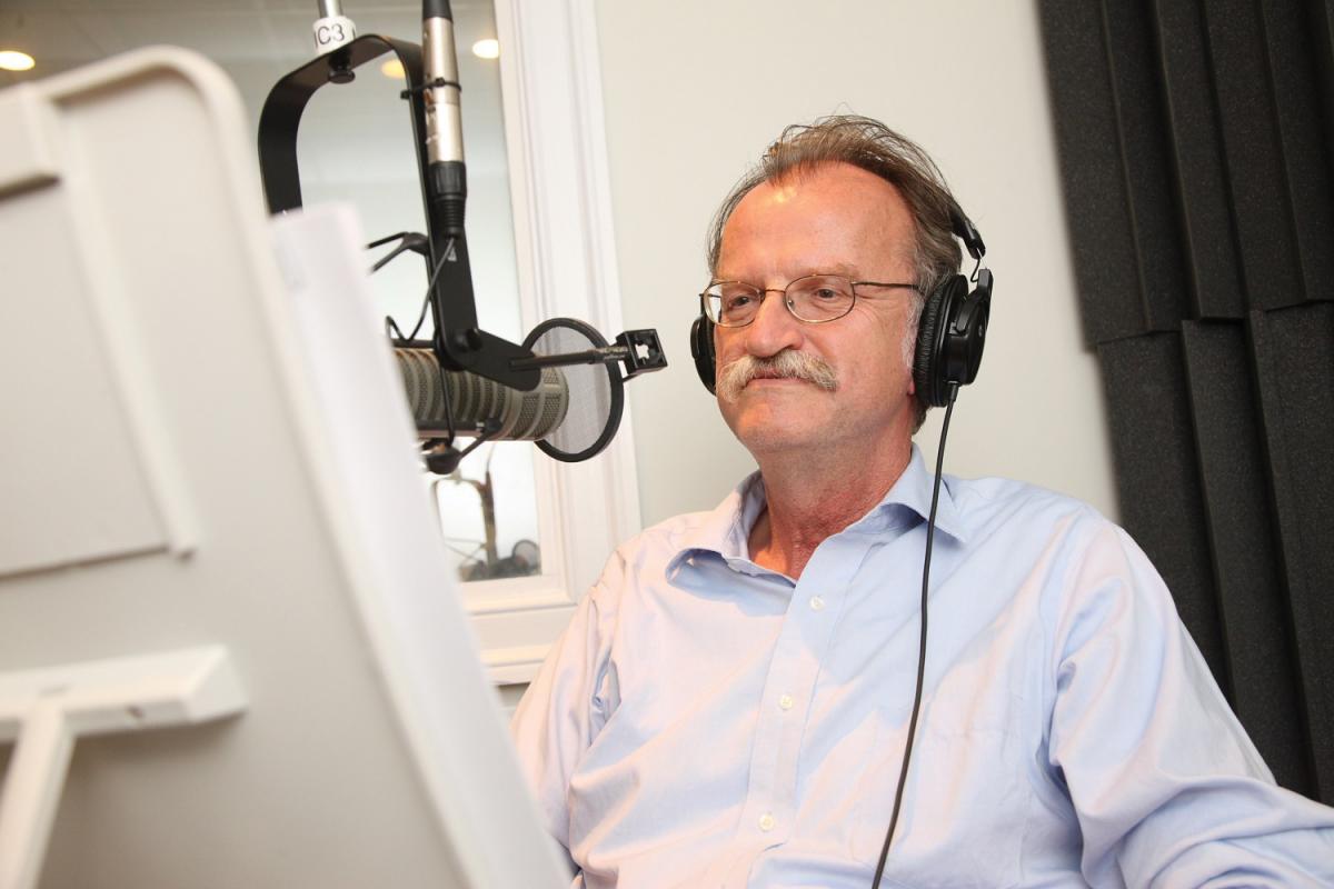 Onuf wearing headphones, standing at a recording microphone