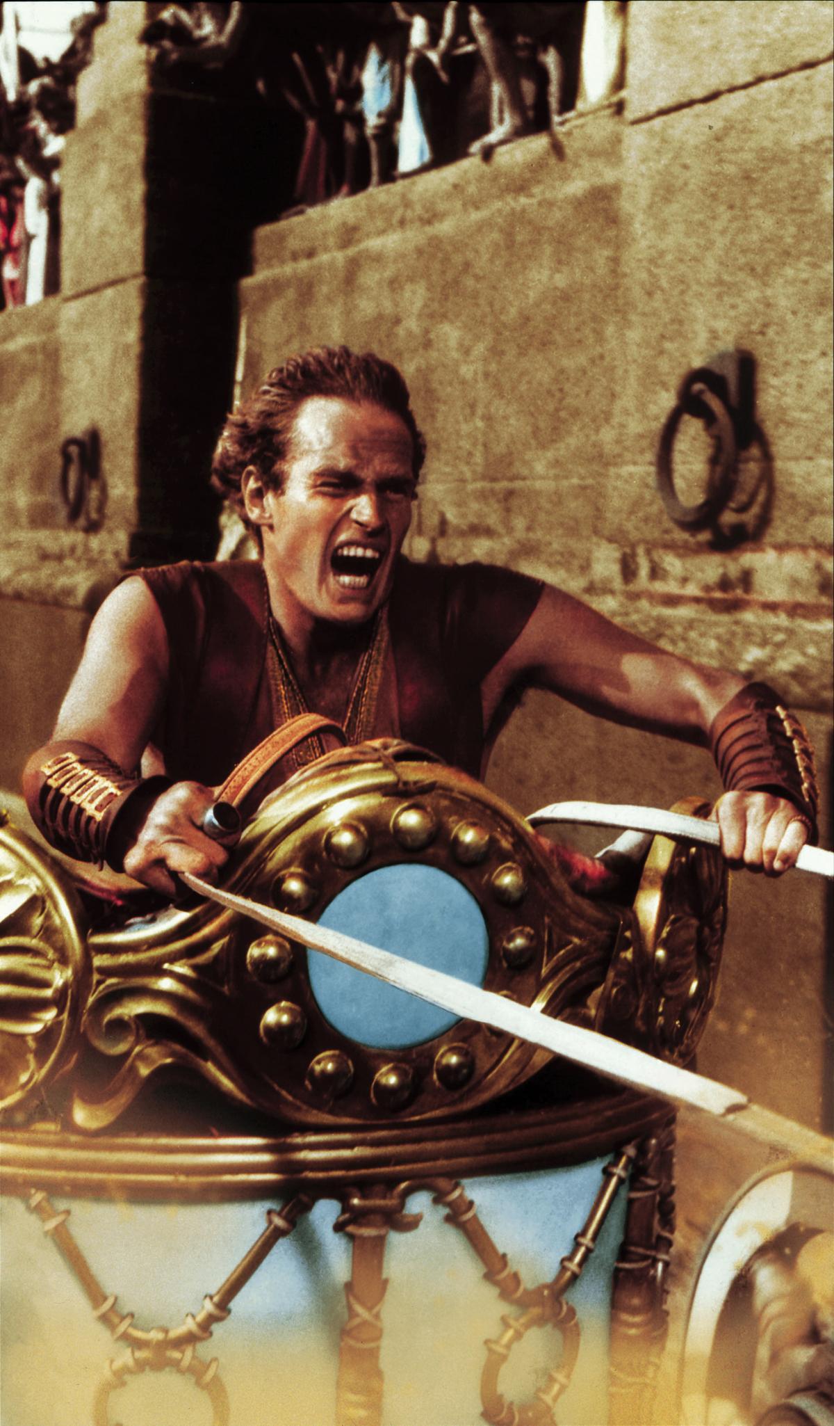 Heston, yelling, pulls on the reins of a chariot during a scene in Ben-Hur the movie