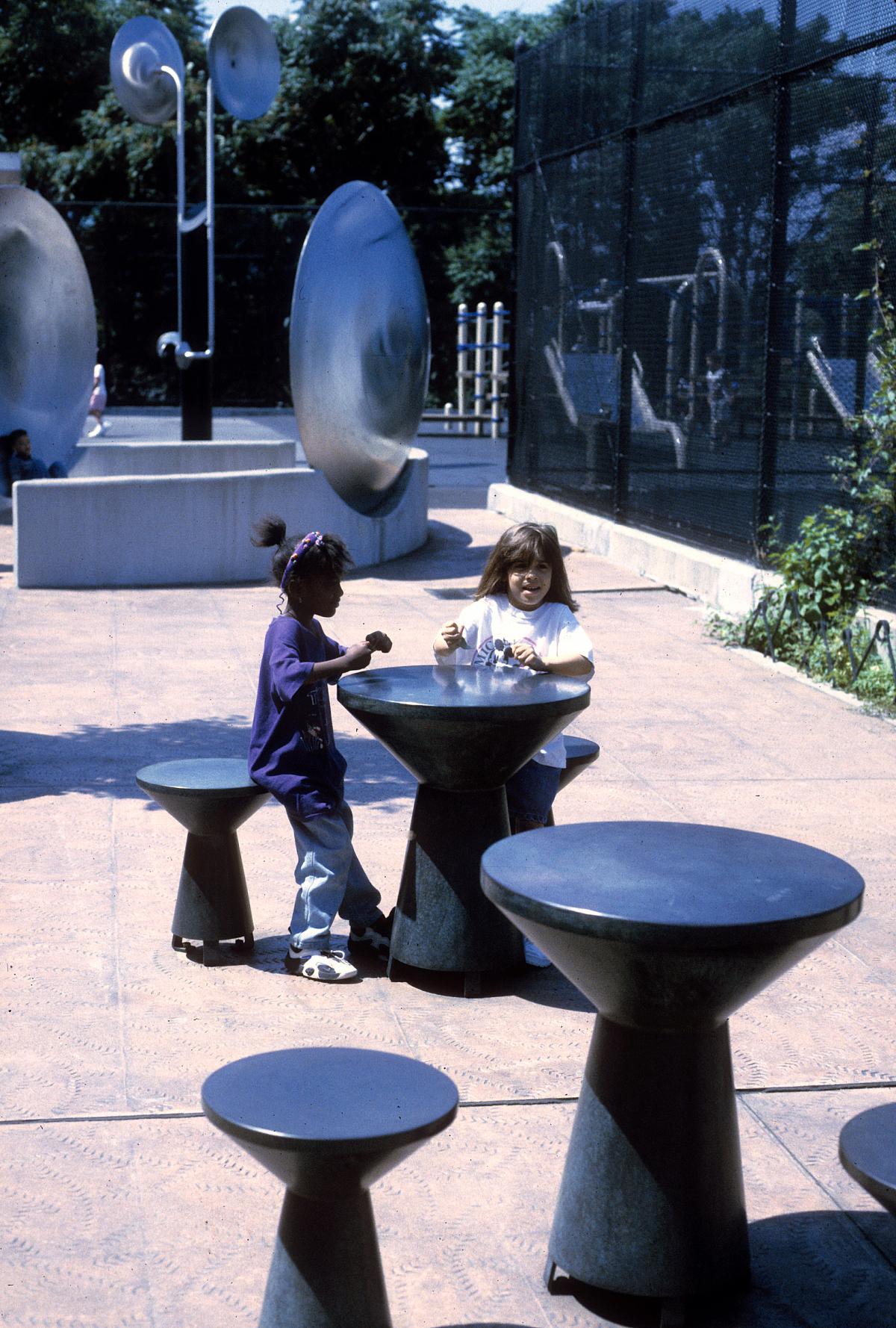 Two girls play at a mushroom-shaped table