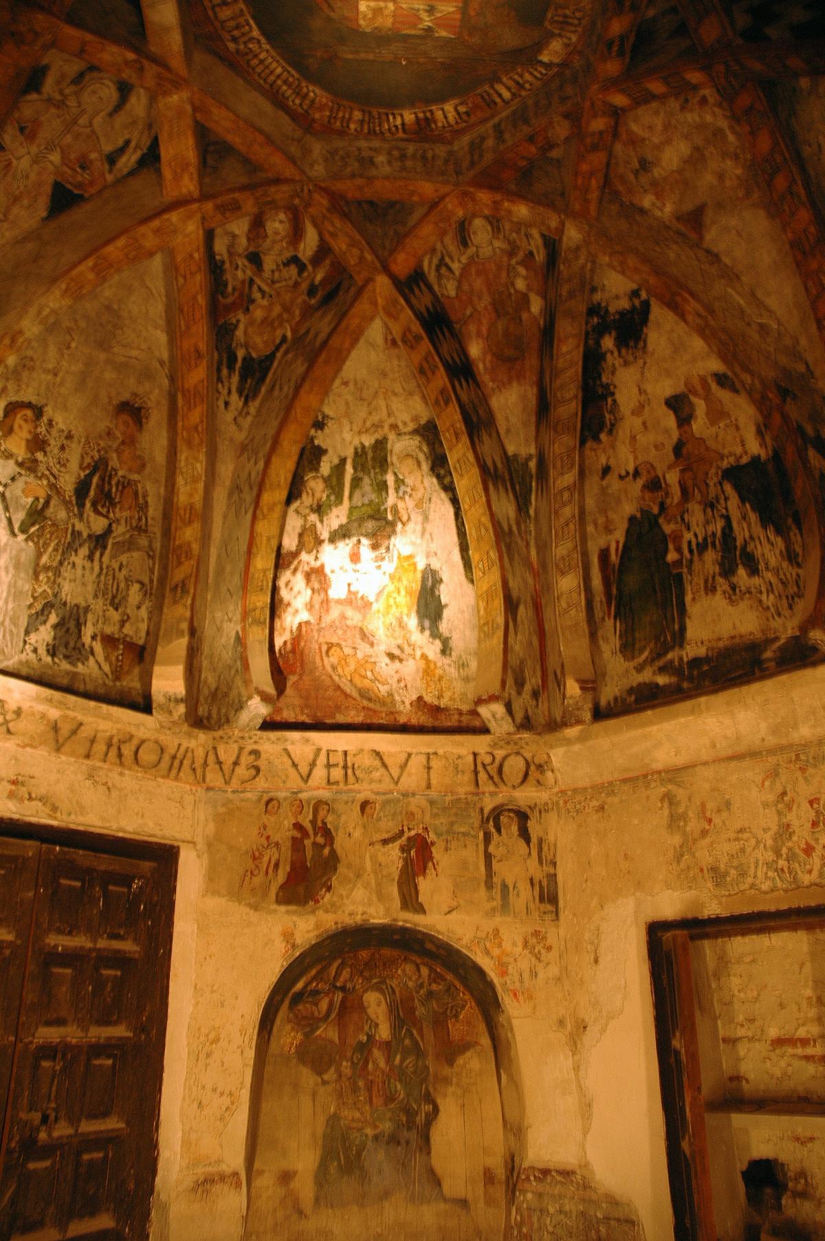 Paintings of saints adorn the vaulted ceiling, lit by torchlight