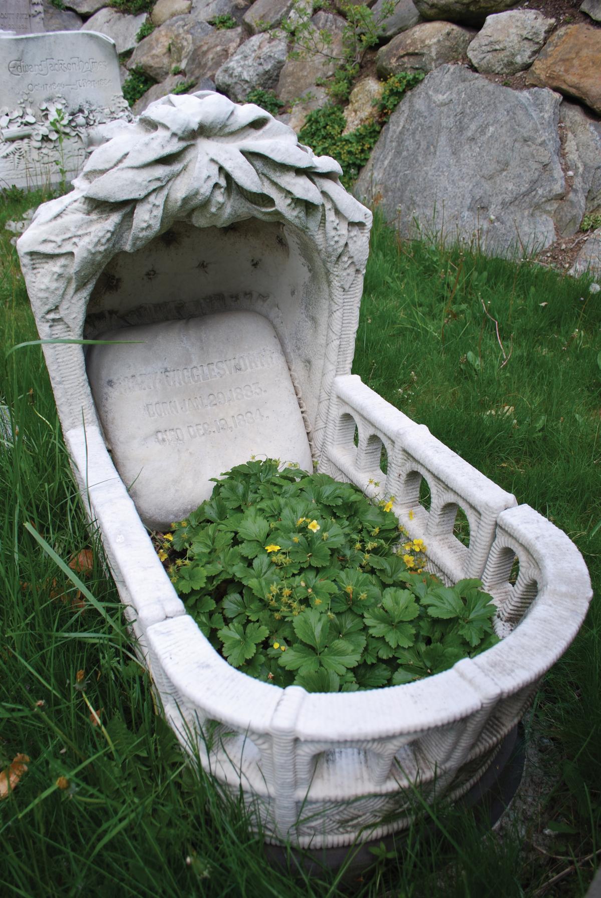 Photograph of a headstone carved into the shape of a cradle