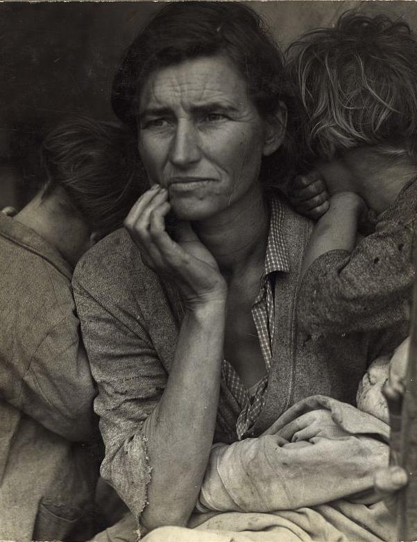 A mother, holding her two children, rests her chin in her hand and looks off