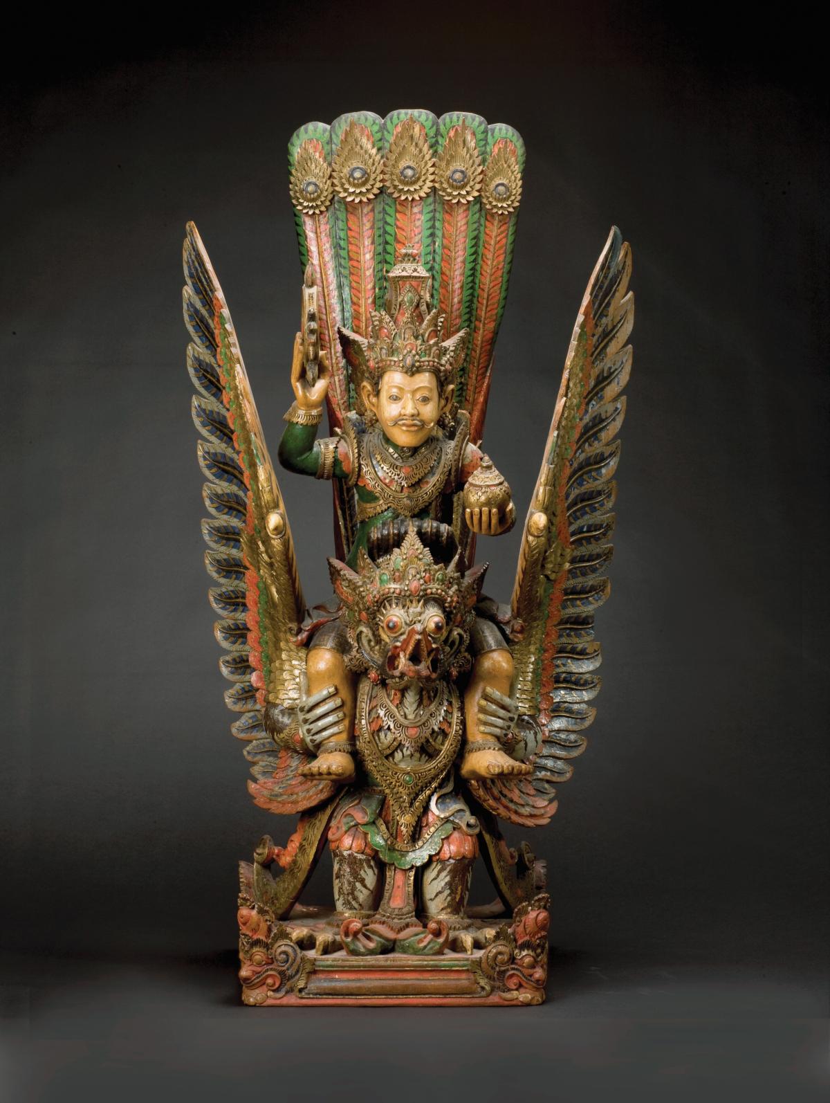 Gold statue of Wisnu, sitting on top of Garuda, painted with aqua, orange and black details