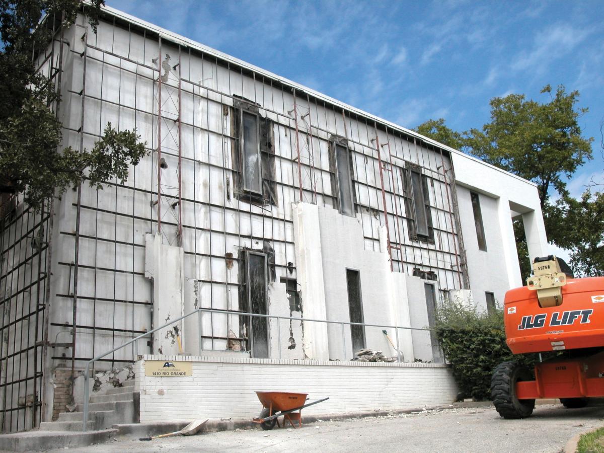 Scaffolding covers the front of the building, while an orange bulldozer sits parked in front