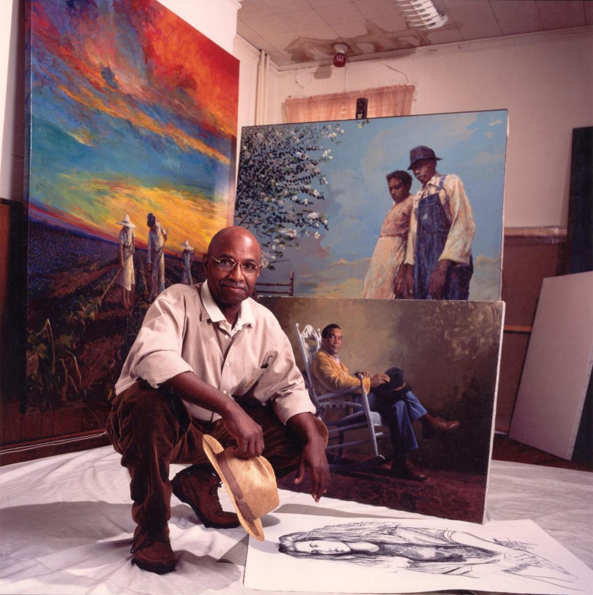 Color photo of Simmie Knox kneeling in his art studio.