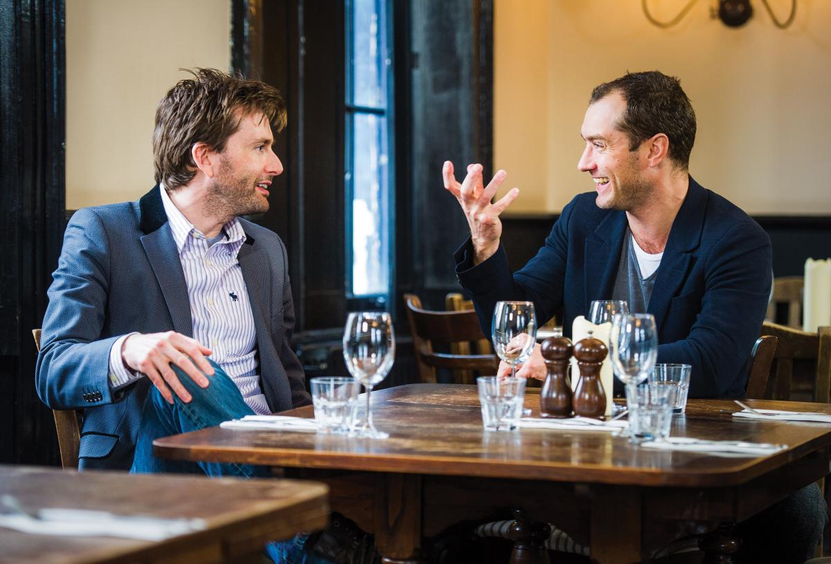 Tennant and Law sit at a table, set with water glasses, laughing and talking