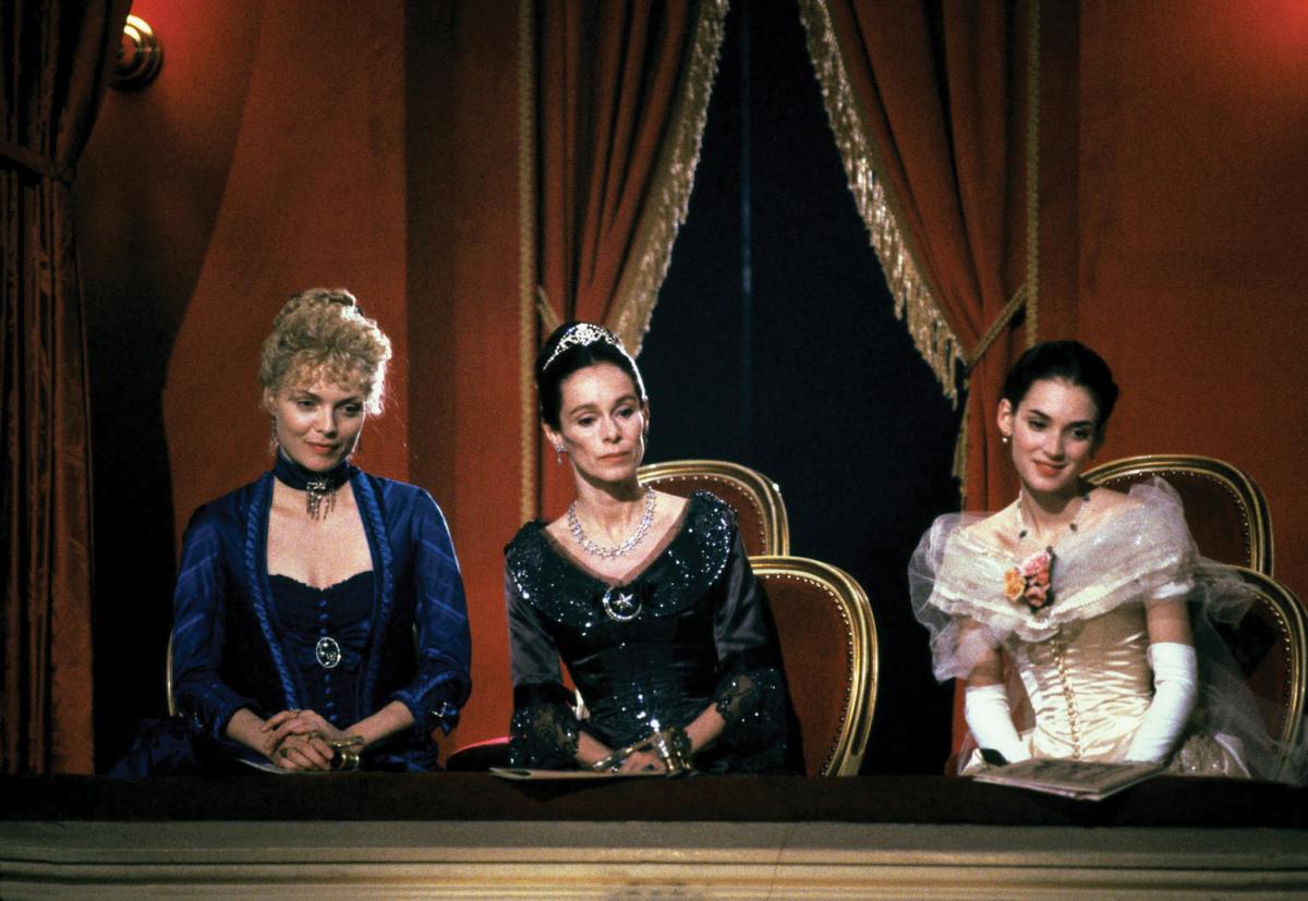 The three actresses, sitting in a velvet draped opera box, wearing elaborate velvet and chiffon dresses