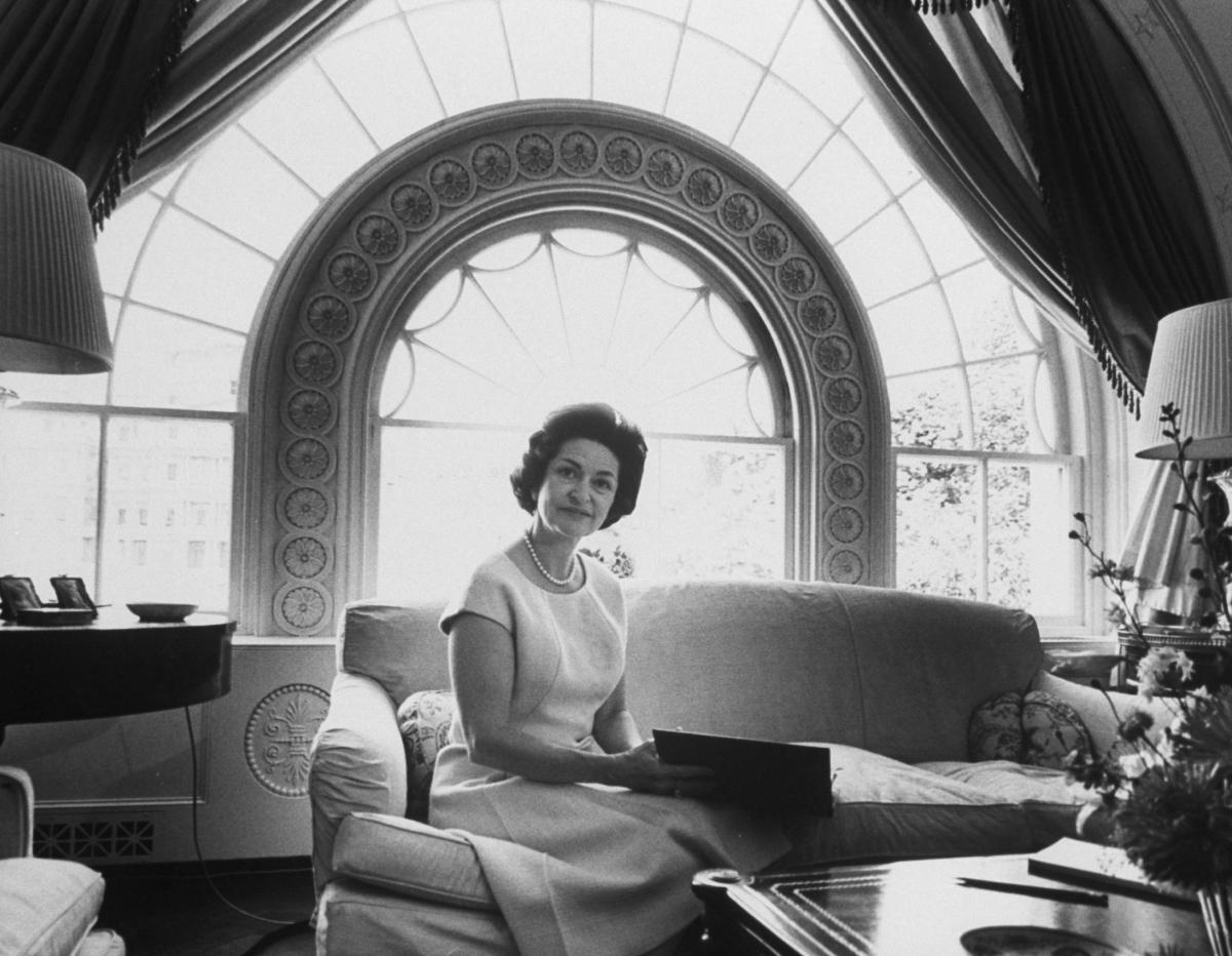 Black and white photograph of Lady Bird Johnson sitting on couch in White House