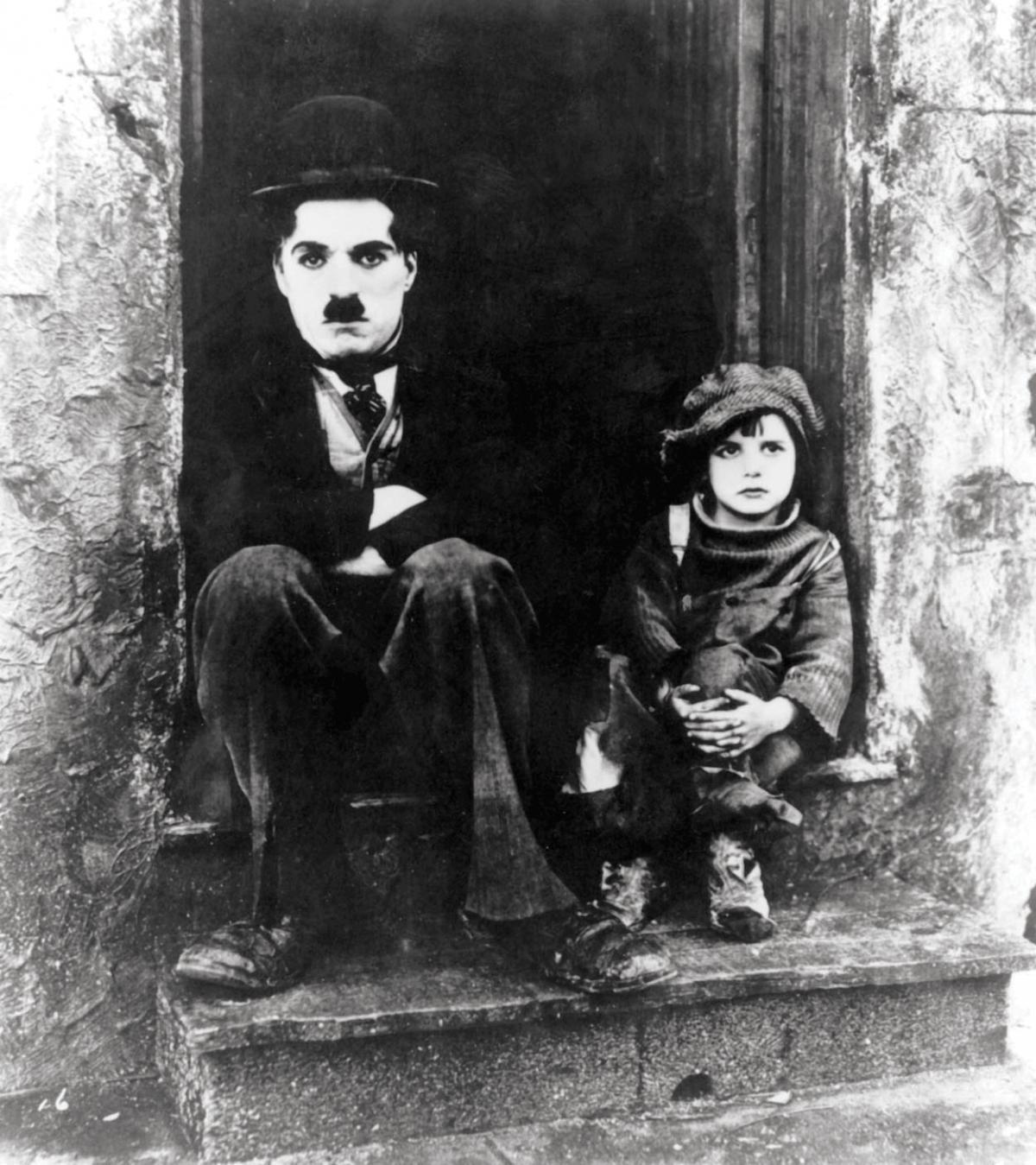Black and white still of Charlie Chaplin and Jackie Coogan sitting on stoop