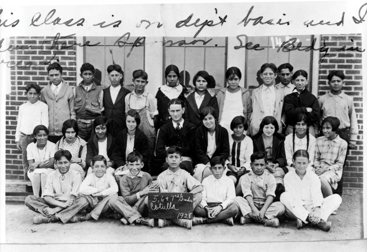 Young Lyndon Johnson, sitting amongst Mexican-American schoolchildren in front of a school building