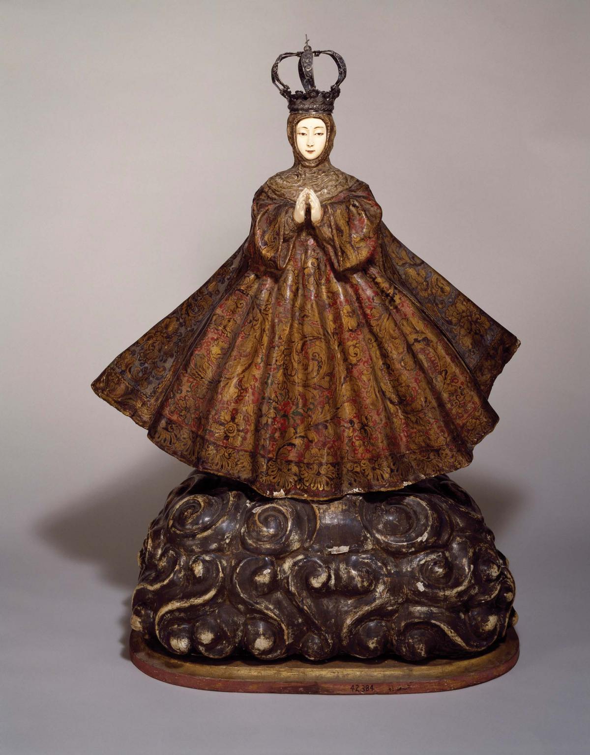 ivory statue of Mary, wearing a wide, brown, embroidered skirt and crown