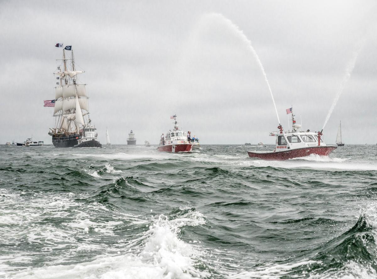 Fireboats and the Morgan on a choppy sea, with grey skies