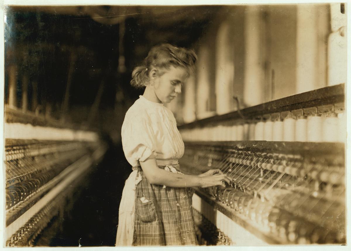 Sepia-colored photograph of a girl working in a mill.
