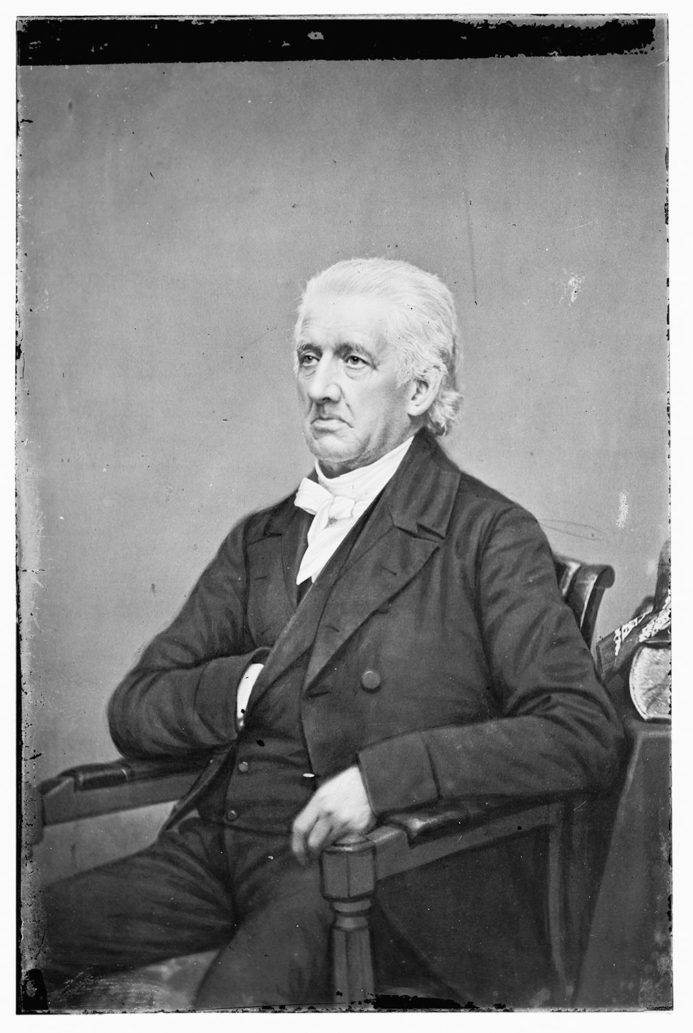 black and white photo of Lyman Beecher, wearing a black suit and white cravat, seated with his hand in his pocket