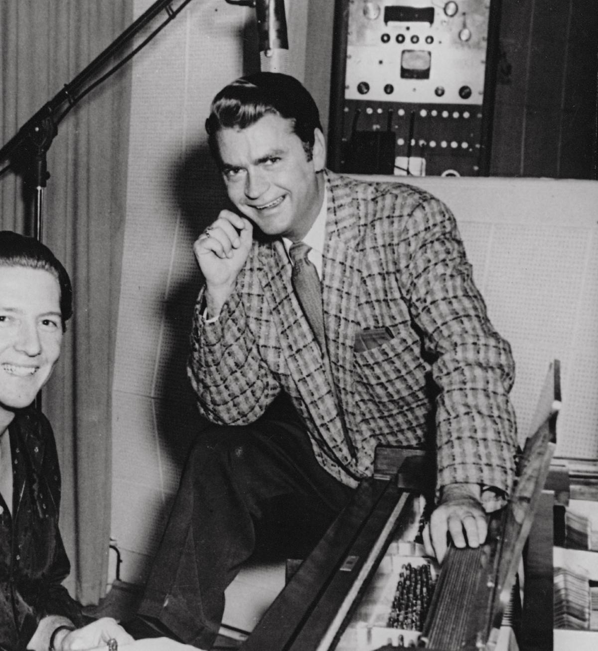 Sam Phillips in a checkered suit, resting his chin on his hand