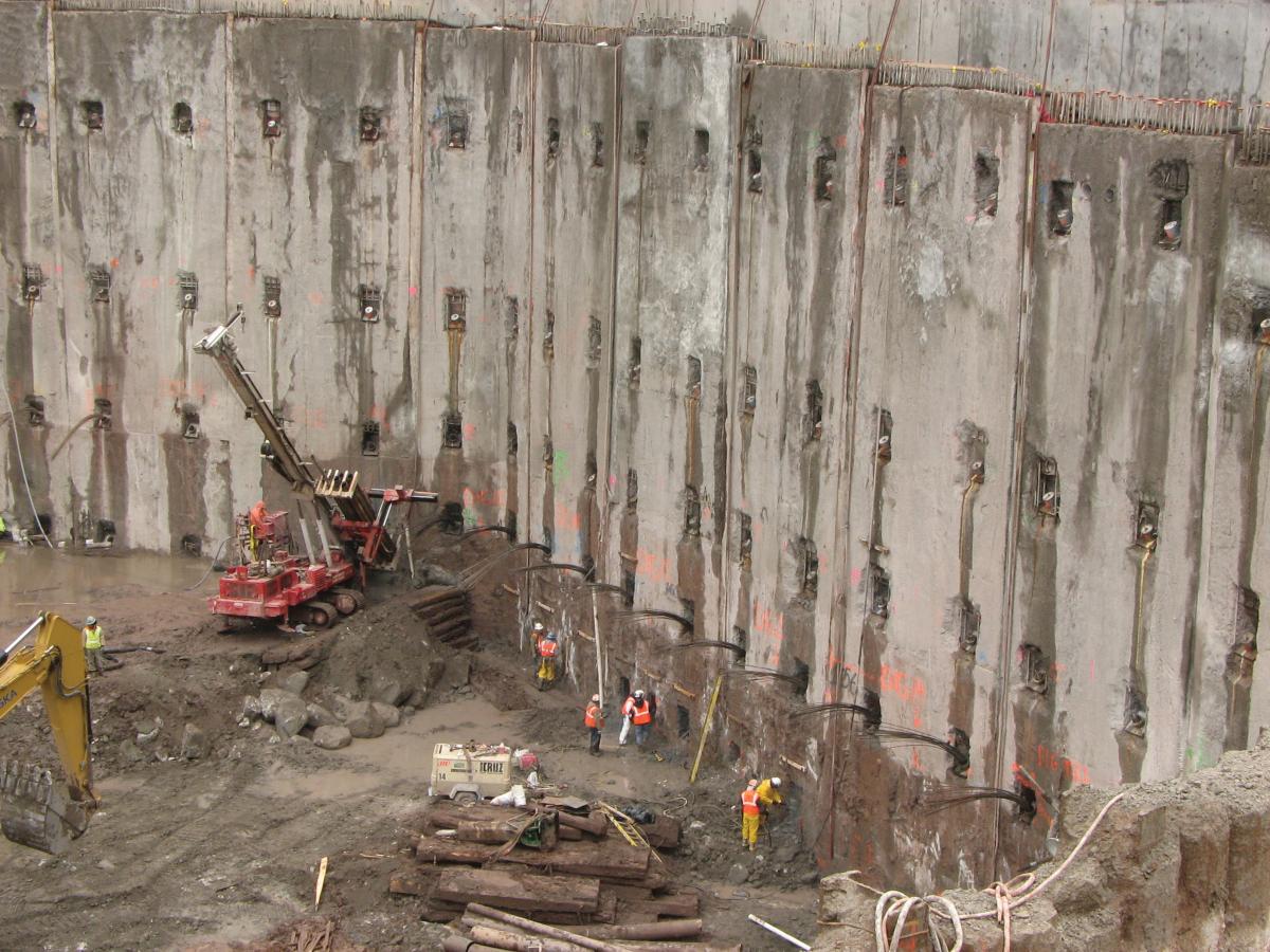 Photograph of a large cement wall with construction equipment