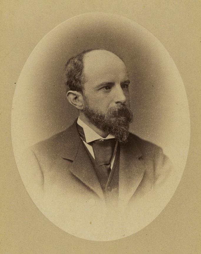 Sepia photograph of Adams, in a suit, with a beard and mustache