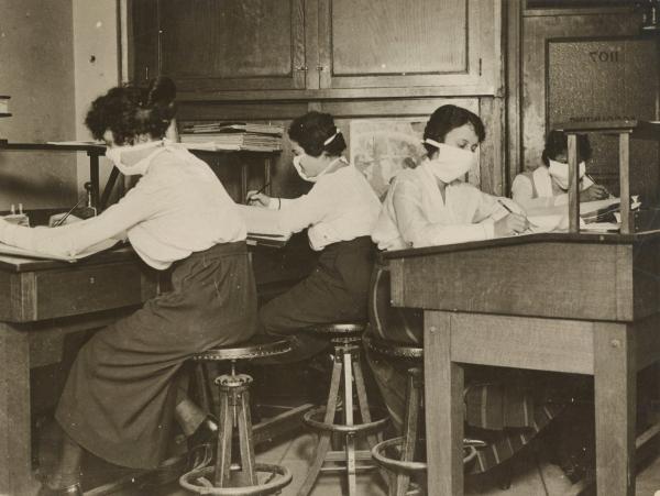 Mask for Protection Against Influenza: Girl clerks in New York at work with masks carefully tied about their faces.