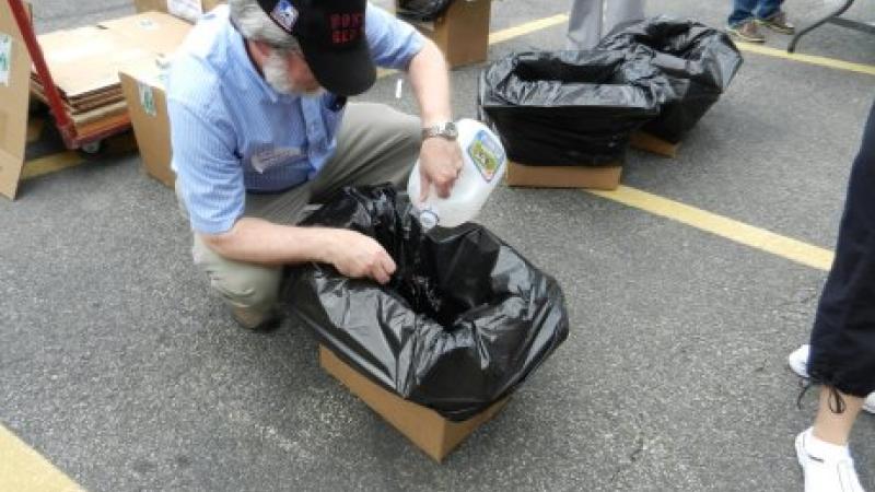A man crouching over a cardboard box, where he is inserting the negative of a photograph