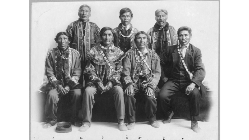 Group of Native American men, half seated, half standing up