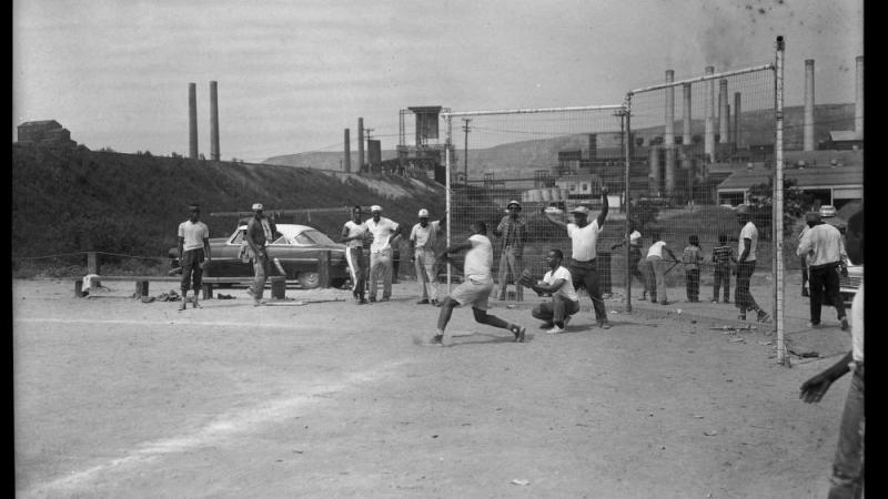 Sandlot baseball players outside steel mill, c. 1955