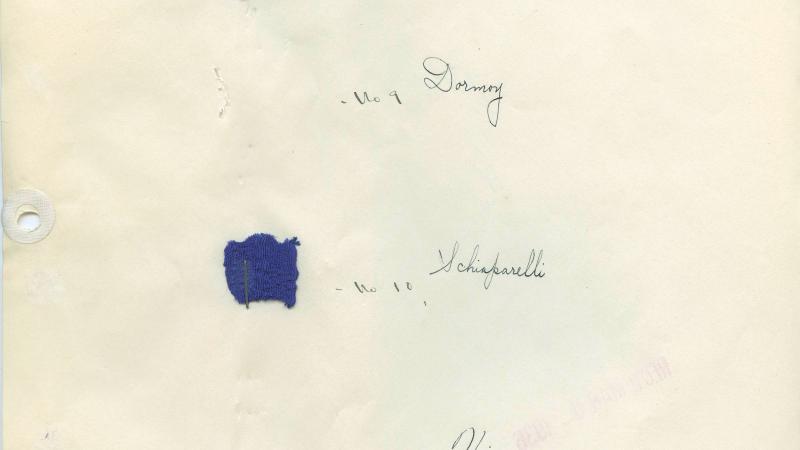A yellowing piece of paper with small tufts of fabrics in various shades of blue, labeled in script with which fashion house it came from
