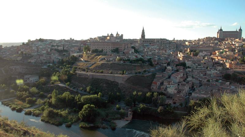 View from across a river of Toledo in late afternoon sunlight