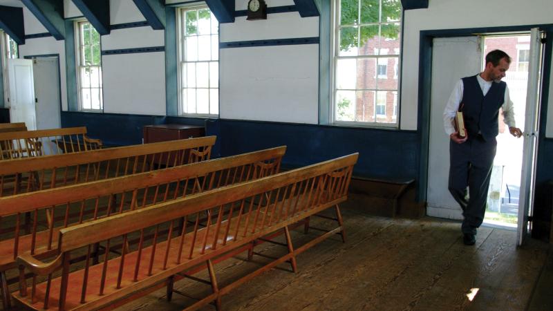 man entering an empty room filled with pews