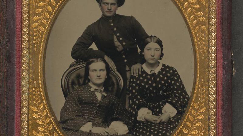 Framed black and white photo of a Union soldier posing with two women.