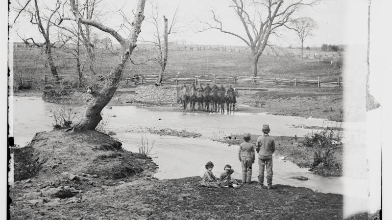 Black and white photo of a creek with Union cavalry in formation on the other side.