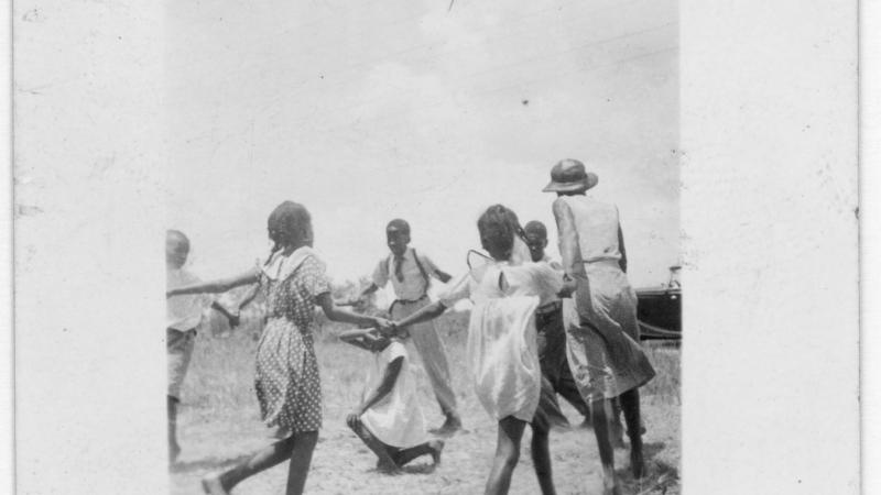 Black and white photo of African American children playing ring-around-the-rosie.