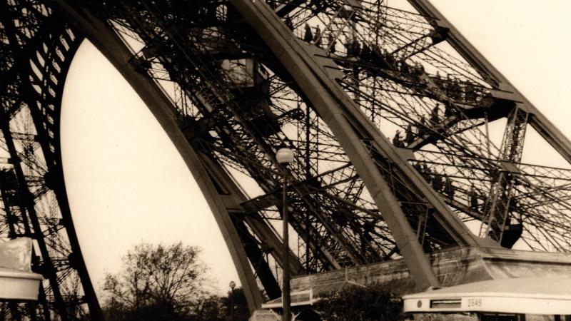 Sepia-colored photo of German soldiers scaling the Eiffel Tower during the occupation of France.